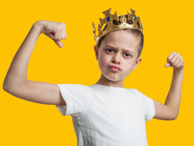 Bambino che mostra i muscoli e indossa una corona