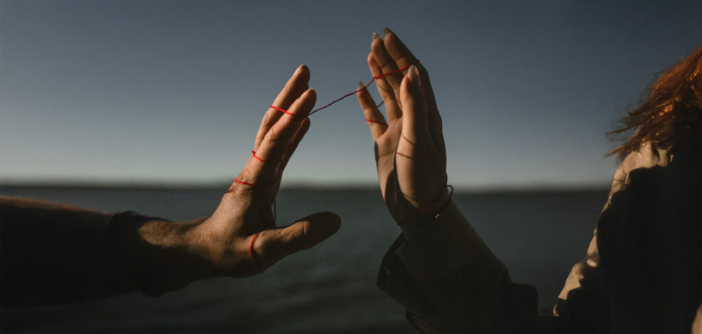 mani legate da un filo rosso, metafora della connessione e della coesione